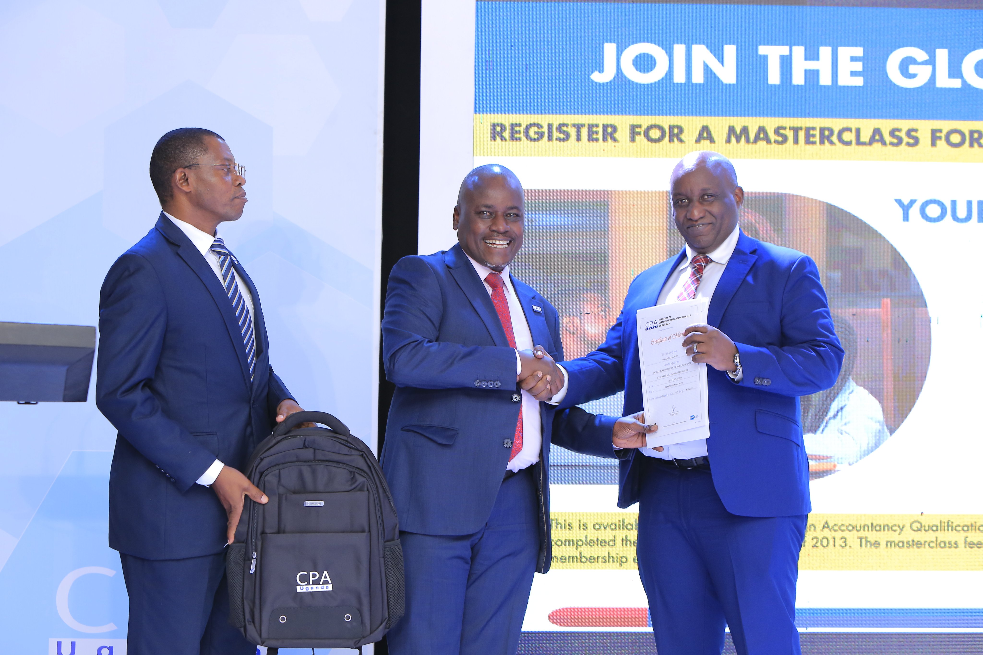 The Vice President ICPAU Council, CPA Ronald Mutumba (center) the  CEO ICPAU, CPA Derick Nkajja (left) hand over tokens of appreciation to CPA  Joshua Karamagi, MD UETCL (right), one of the presenters at the 2nd C-Suite Forum.
