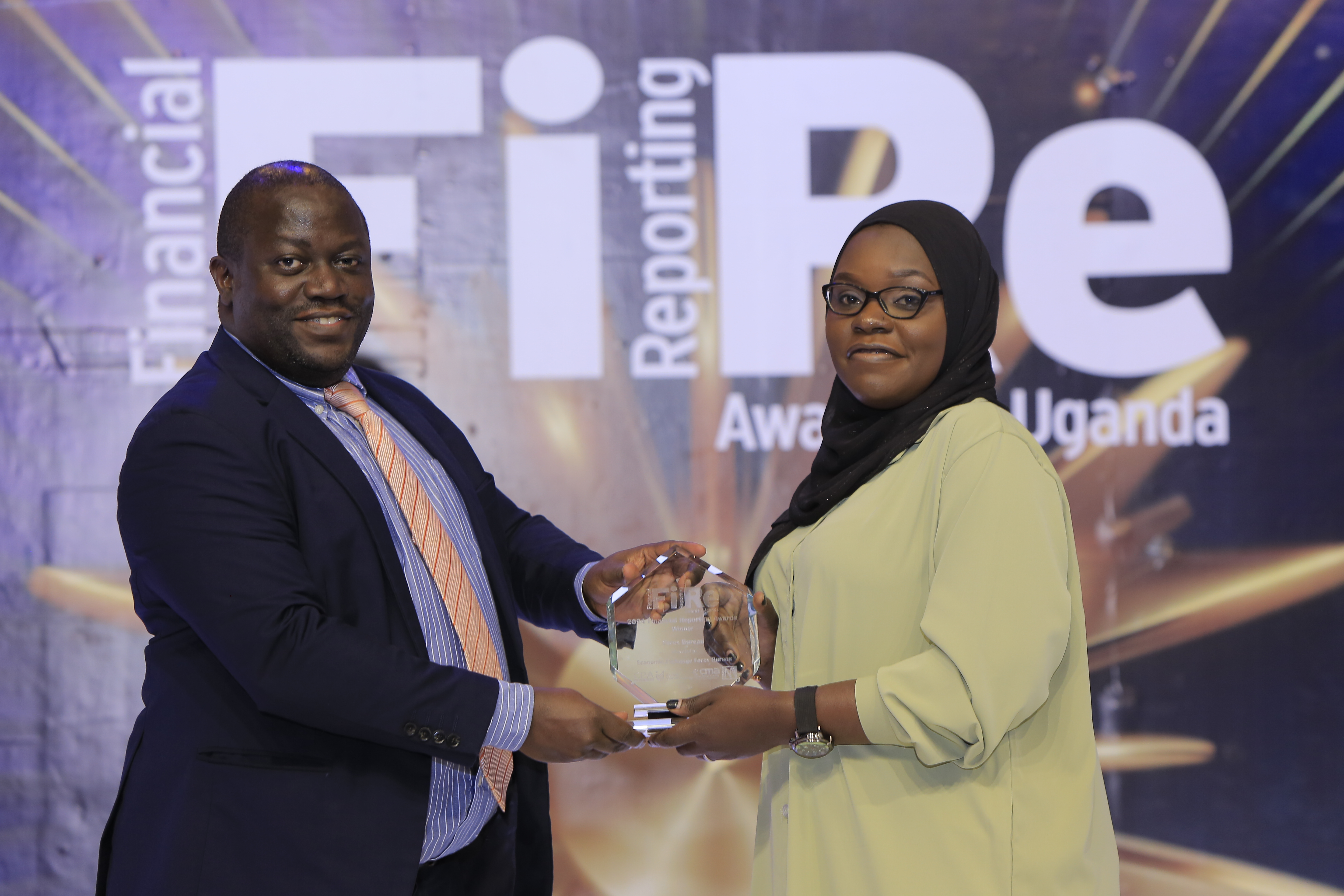 Economic Exchange Forex Bureau representative receiving an award of winner for achievement in financial reporting under the Forex Bureaux category from Mr Dickson Seguya Director of research and development at CMA at the FiRe awards ceremony on 6 November 2024 at Serena Hotel Kampala