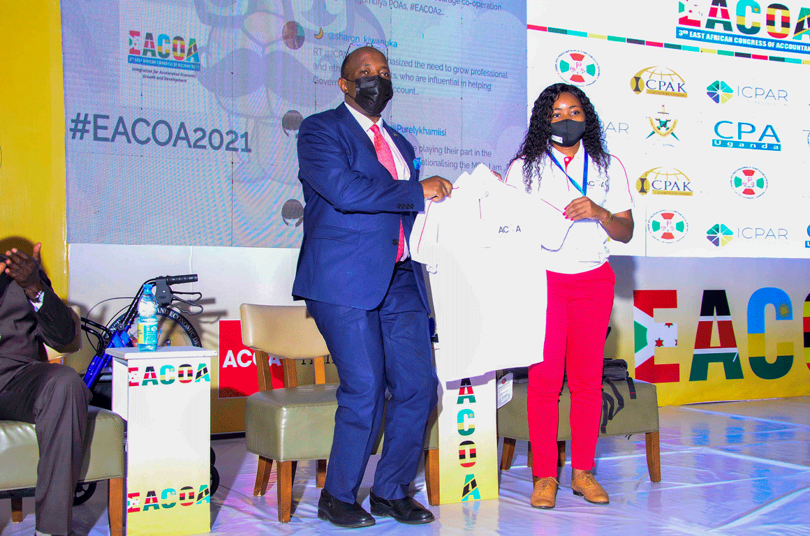 CPA Frederick Kibbedi recieves a gift from a representative of OCAM